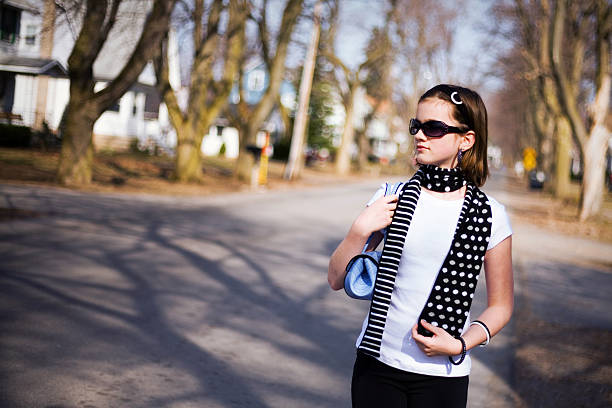 Attractive preteen walking along a residential street in a small town.