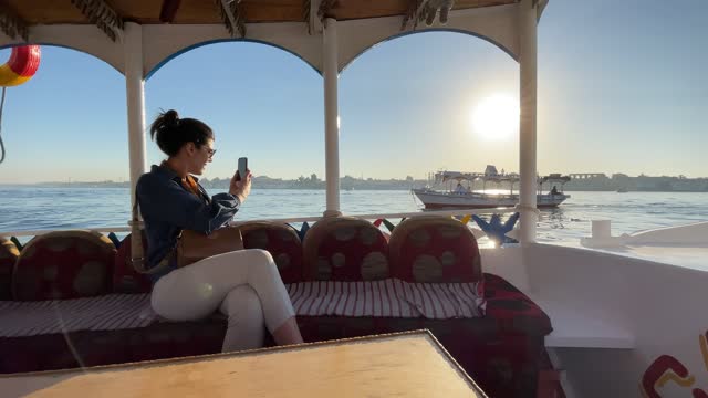 Mid adult woman filming on the mobile phone in a boat in Nile River, Egypt