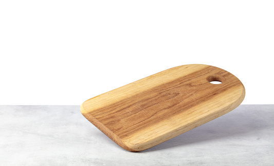 Cutting board falling on a grey stone table. Isolated on a white background. Culinary background. Empty wooden cutting board, product display space.