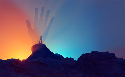 Man stands on top of a mountain or a hill. In front of him is a giant hand raised in the air. Concept image of meeting god, the afterlife or surreal dreaming. It could also be a paranormal meeting.