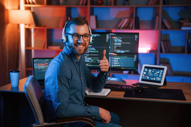 Showing thumb up. Professional programmer is working indoors. Neon lighting Showing thumb up. Professional programmer is working indoors. Neon lighting. debug stock pictures, royalty-free photos & images