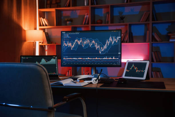 Computer with stock exchange graph on display is in the dark room with neon lighting stock photo