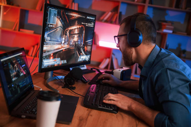 istock Concentrated man is playing the shooter game on his computer. Neon lighting 1459166714
