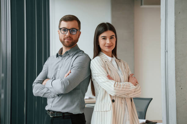 Man with woman is standing and posing. Successful team are working together in the office. Conception of business stock photo