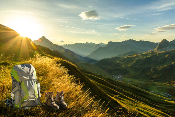 早朝の日の出と山のシルエットのハイキング用具。美しい日差しと太陽の光の中でバックパックとブーツ。フォアアールベルク州、レヒタール、オーストリア。 - lech valley ストックフォトと画像
