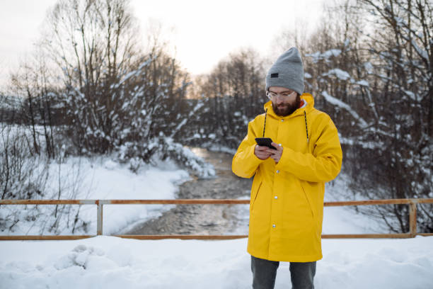 istock Young man using smartphone in nature on a snowy day 1459174354