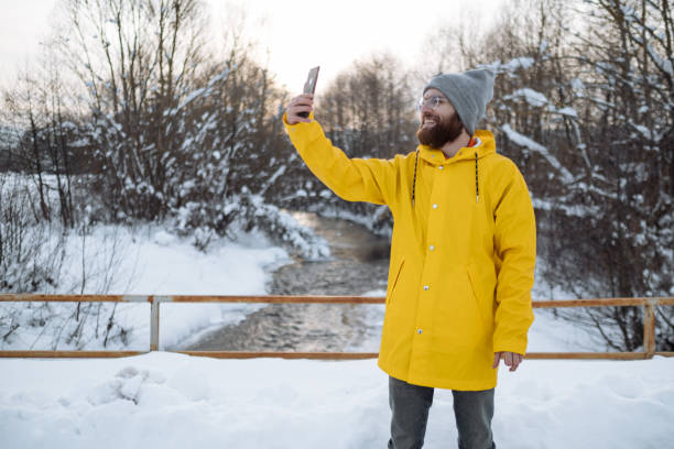Young man using smartphone on snowy day