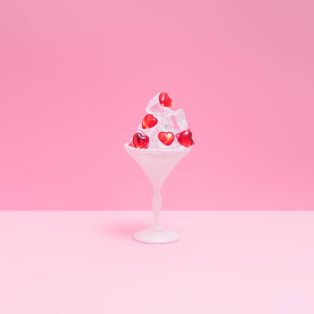 copa de cóctel llena de cubitos de hielo con corazones rojos. amor surrealista o idea de moda en un estilo minimalista. - summer party drink umbrella concepts fotografías e imágenes de stock