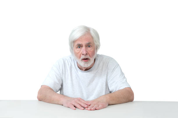 istock Surprised Old Man Sitting At Table Isolated On White 1459175827