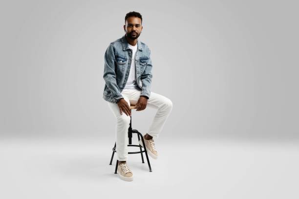 istock Handsome young african american guy sitting on stool, posing in studio - isolated 1459177444