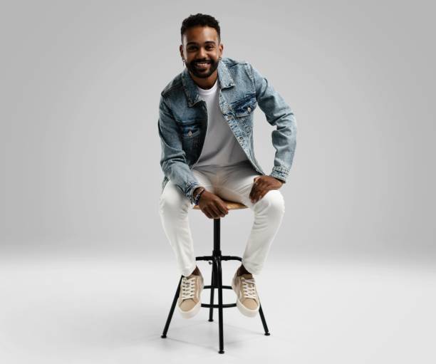 istock Handsome young african american guy sitting on stool, posing in studio - isolated 1459177453
