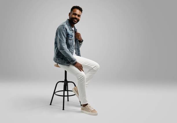 istock Handsome young african american guy sitting on stool, posing in studio - isolated 1459177465