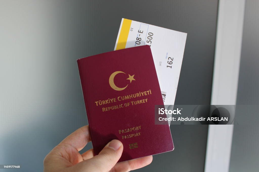 Turkish burgundy passport and flight ticket in the passenger's hand. Emigration and Immigration Stock Photo