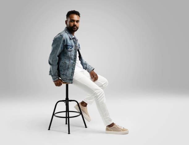istock Handsome young african american guy sitting on stool, posing in studio - isolated 1459177487