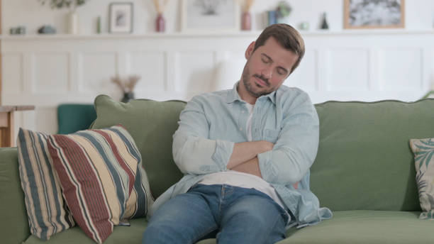istock Young Man Sleepy While Sitting on Sofa at Home 1459177782