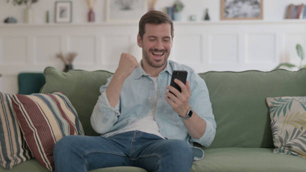 istock Young Man having Success on Smartphone at home 1459177959