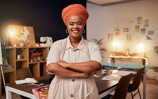 Portrait, fashion and proud fashion designer in her workshop or design studio ready to make clothes. Front, arms crossed and happy tailor or seamstress working in her clothing manufacturing business