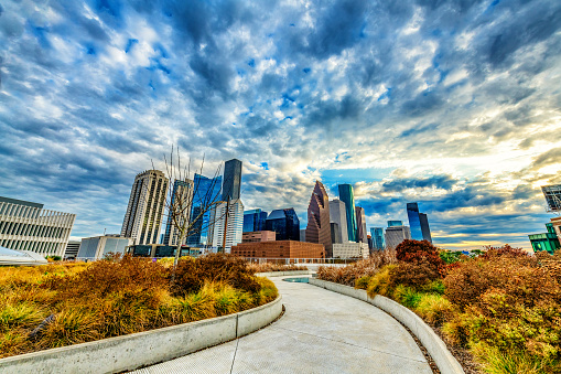 A curved sidwalk leading toward the skyline of the city of Houston, Texas.