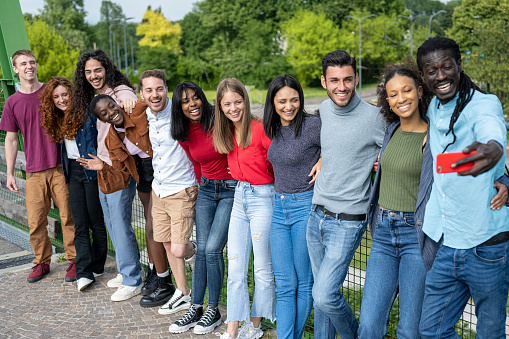 Big group of cheerful young friends taking selfie portrait, happy diverse people looking at the camera and smiling, concept of community, youth lifestyle and friendship