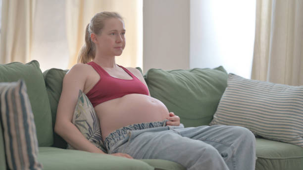istock Pregnant Woman Coming and Sitting on Sofa 1459182949