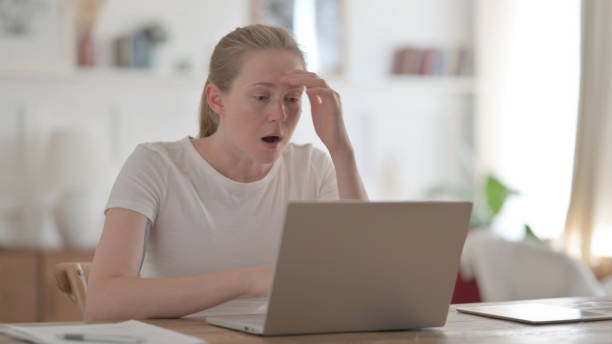 istock Beautiful Young Woman Reacting to Loss While using Laptop 1459183857