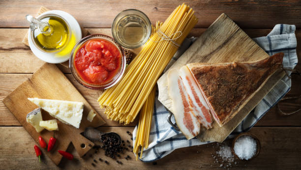 Bucatini or spaghetti all'Amatriciana, famous Italian recipe, basic ingredients on wooden table, still life, top view. Ingredients for Amatriciana pasta, original recipe. all'amatriciana stock pictures, royalty-free photos & images