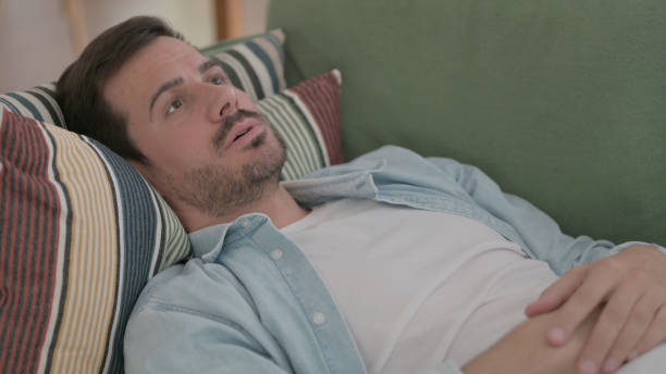 istock Tense Young Man Lying on Sofa in Stress, Close up 1459187198