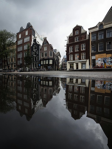 Typical Amsterdam architecture street houses reflection in rain water puddle city center in Holland Netherlands