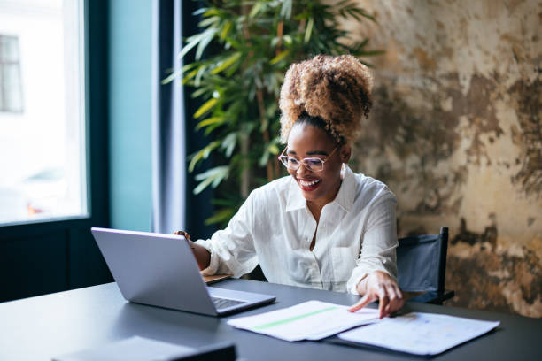 istock Happy Businesswoman Holding Document While Using A Laptop Computer In The Cafe 1459190037