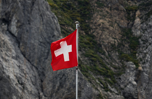 Bandera suiza ondeando en el viento en las montañas Alpstein fondo rocoso alpino Appenzell Suiza photo