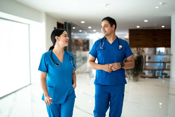 Nurse coworkers walking and talking on the hospital Nurse coworkers walking and talking on the hospital walking aide stock pictures, royalty-free photos & images