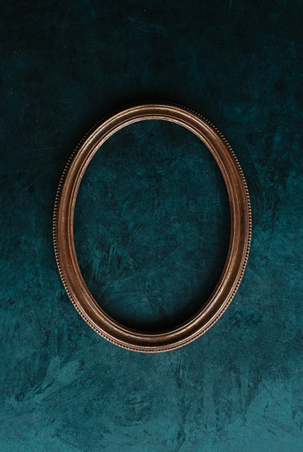 Vintage oval frame, openwork wooden bronze color  vertical frame on a old wall background