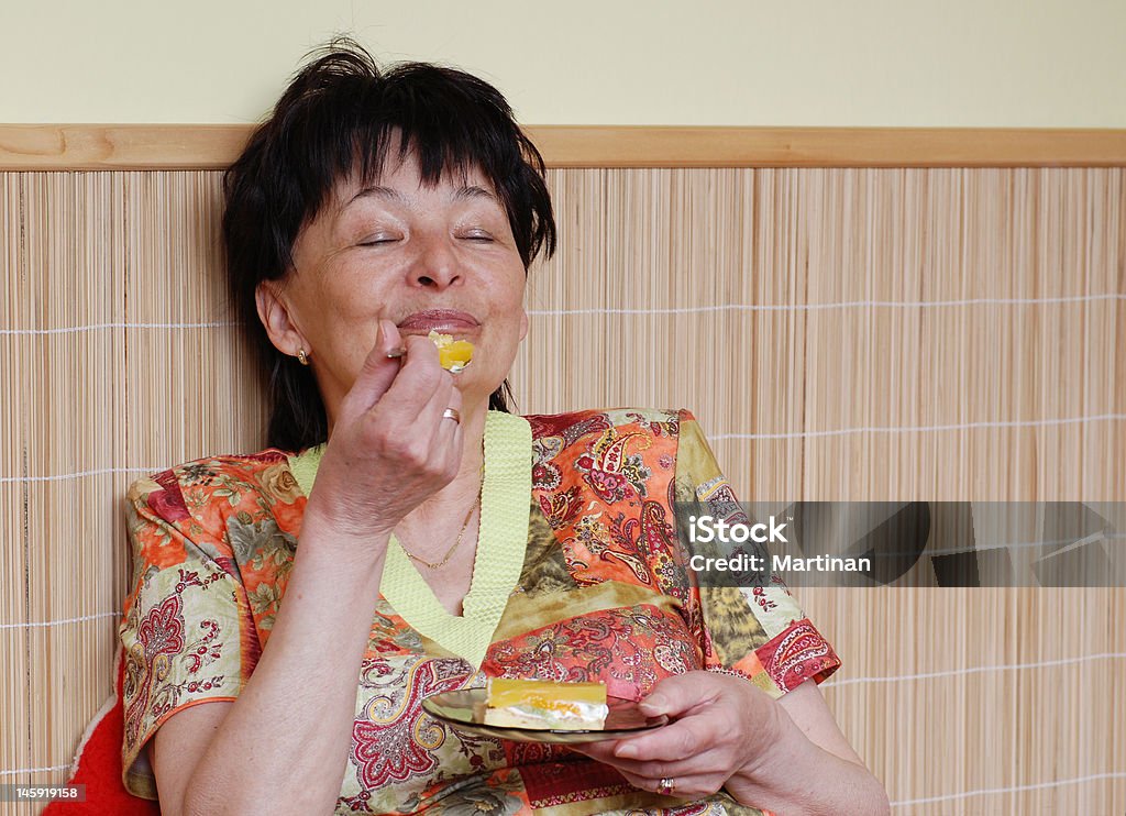 Sênior mulher sabores bolo - Foto de stock de Comida royalty-free
