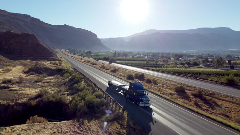 Drone pov of a Semi Truck driving down the interstate at dawn.