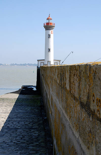 lighthouse with pier and rocks stock photo