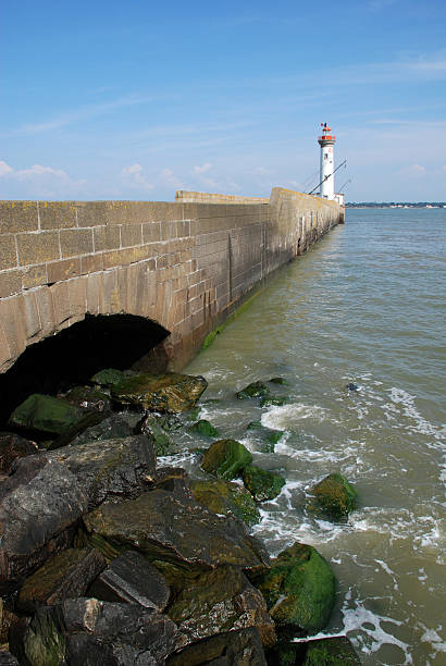 lighthouse with pier and rocks stock photo