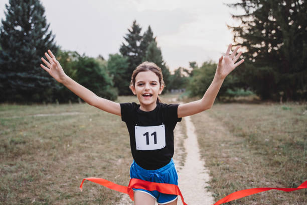 Cute girl runner crossing finish line in a race competition in nature. stock photo
