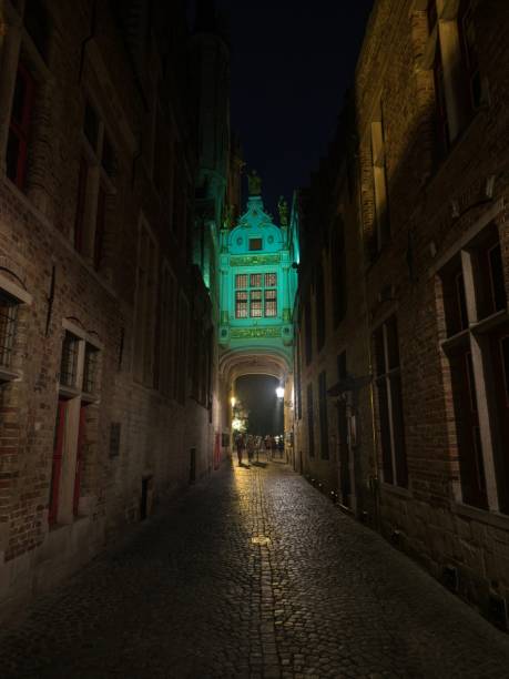 blinde-ezelstraat blind donkey street arch bridge iluminado oscuro estrecho callejón de adoquines por la noche en brujas bélgica - bruges town hall fotografías e imágenes de stock