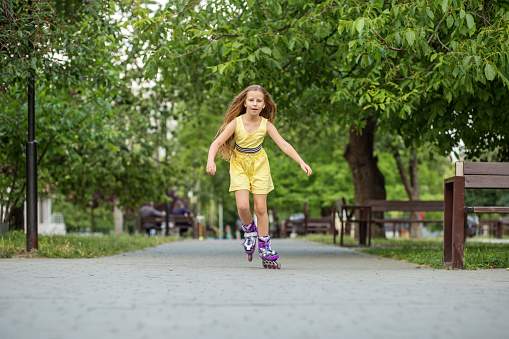 Young fit woman on roller skates riding outdoors on urban street with open arms. Smiling woman with rollerblading on sunny day