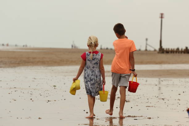 istock Brother and sister walking along beach together 1459199480