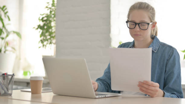 istock Beautiful Young Woman Reading Documents, Doing Paperwork in Office 1459200969