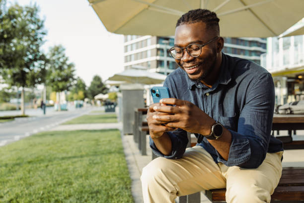 istock Young man sitting on the bench using smart phone 1459201174