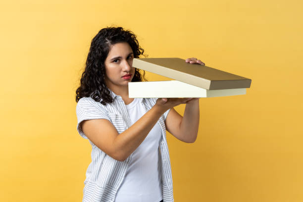 istock Woman opens wrapped present box, expressing disappointment, looking at camera, expressing sorrow. 1459201388