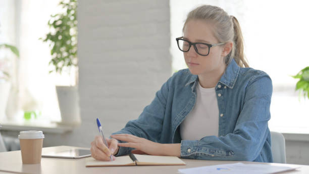 istock Young Woman Writing on Paper in Office 1459201624