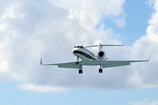 Private / corporate / business jet just before landing. Blue partly cloudy sky.
