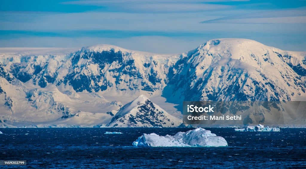 Icebergs in blue water; mountains Icebergs in blue water; mountains in background Antarctica Stock Photo