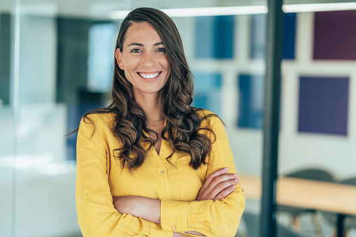 Confident businesswoman at her workplace at modern office. Portrait of businesswoman happily smiling and looking at camera