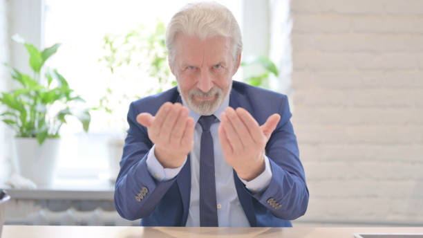 istock Inviting Senior Old Businessman Pointing at the Camera 1459204301