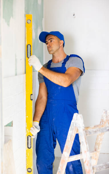 istock Professional man builder in work clothes holding level in hands and checking of installing tiles 1459204843