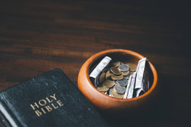 One tenth or tithe is basis on which Bible teaches us to give one tenth of first fruit to God. coins with Holy Bible. Biblical concept of Christian offering, generosity, and giving tithes in church. stock photo